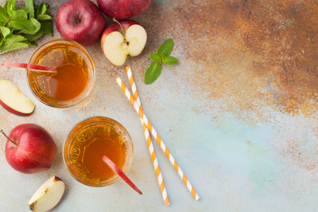 Two glasses of red Apple juice with mint and ice on an old rusty table. Soft drink on a blue background. Top view with copy space.の写真素材