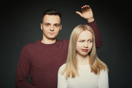 Portrait of a beautiful young couple in love posing at studio over dark background.の写真素材