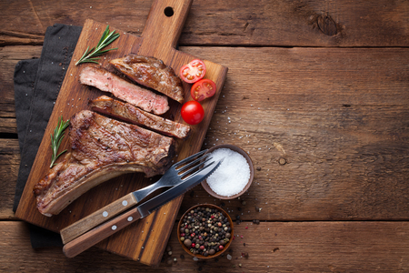 Grilled cowboy beef steak, herbs and spices on a rustic wooden background. Top view with copy space for your text.の写真素材
