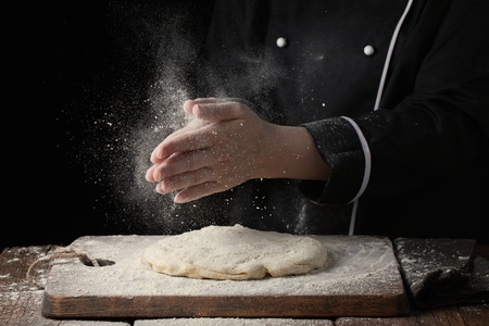Woman chef hand clap with splash of white flour on a black background.の写真素材