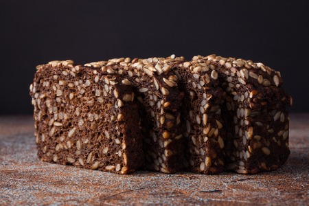 Fresh black bread with sunflower seeds on an old rusty table.の写真素材