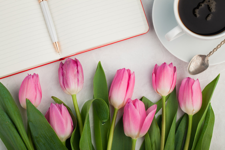Woman working desk with coffee mug, notebook and spring tulip flowers top view in flat lay style.の写真素材