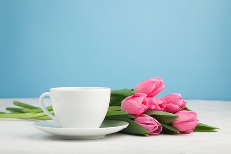 Black coffee in white Cup with pink tulips on light stone background.の写真素材
