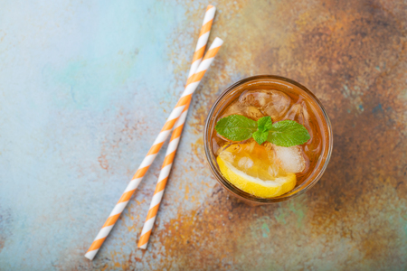 Traditional iced tea with lemon, mint and ice in tall glasses. A glass of refreshing summer drink on the old rusty background. Top view with copy space.の写真素材