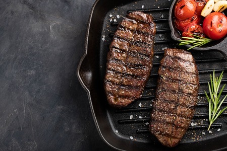Closeup ready to eat steak Top Blade beef breeds of black Angus with grill tomato, garlic and on a...