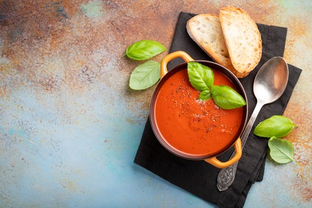 Homemade tomato soup with Basil, toast and olive oil on the stone table. Prepared a vegetarian dish on a rusty background. Top view with copy space.の写真素材