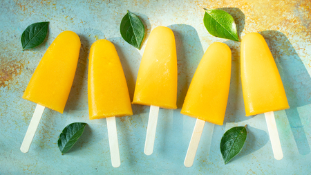 Orange ice pops with juice on a rusty blue background.の写真素材