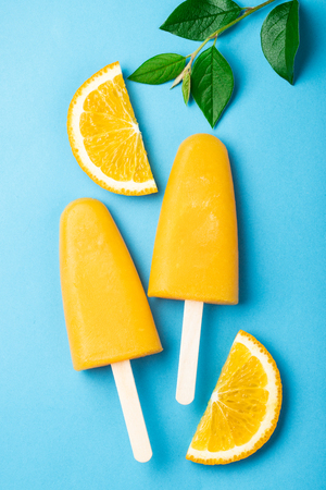 Orange ice pops with juice on a blue background.の写真素材
