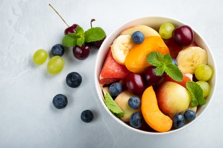 Bowl of healthy fresh fruit salad on a white background. Top view with copy space. Flat lay.の写真素材