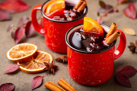 Two cups of autumn mulled wine or gluhwein with spices and orange slices on rustic table top view. Traditional drink on autumn holiday on the background of autumn leavesの写真素材