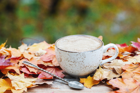 Autumn, fall leaves, hot steaming cup of coffee on wooden table background. Seasonal, morning coffee, Sunday relaxing and still life concept. With copy space for textの写真素材