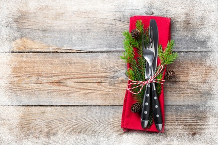 Christmas table setting with christmas decorations. Cutlery, fir cones and towel with snowflakes on old rustic wooden background. Frosty the snow frame. Top view, copy space. Flat lay.の写真素材