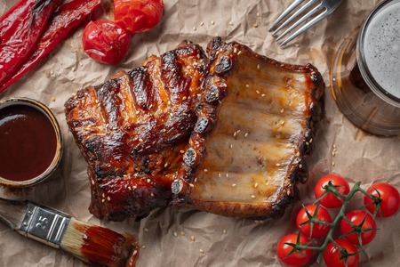 Closeup of pork ribs grilled with BBQ sauce and caramelized in honey on a paper. Tasty snack to beer. Top view. flat lay.の写真素材