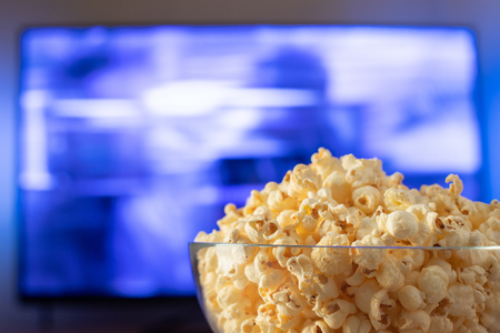 A bowl of popcorn   with TV in the backgroundの写真素材