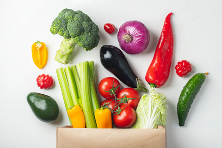 Paper bag with fresh vegetables on white background. Flat lay. Top view.の写真素材