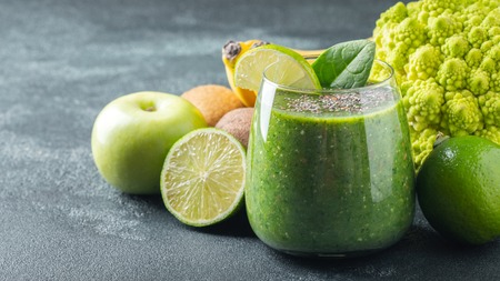 Green fresh healthy smoothie with fruits and vegetables on a dark concrete background. With copy space.の写真素材
