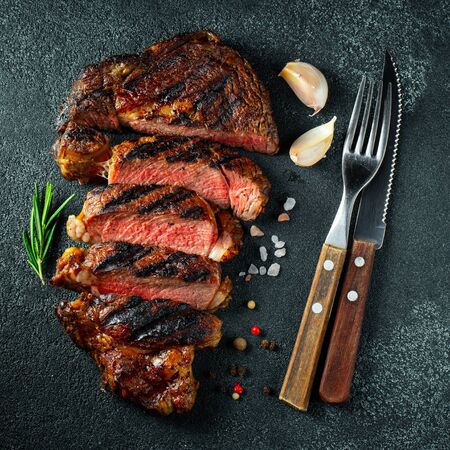 Sliced steak ribeye, grilled with pepper, garlic, salt and thyme on a dark stone background. Top view. Flat lay.の写真素材
