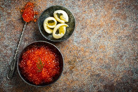 Delicious red caviar in black bowl on a dark concrete background. Top view with copy space. Flat lay.の写真素材