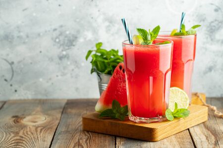 Watermelon slushie with lime and mint, summer refreshing drink in tall glasses on a light blue background. Sweet cold smoothie with copy spaceの写真素材