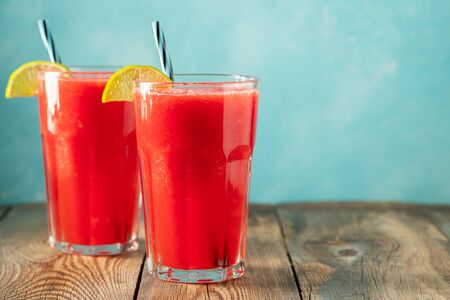 Watermelon slushie with lime and mint, summer refreshing drink in tall glasses on a light blue background. Sweet cold smoothie with copy space.の写真素材