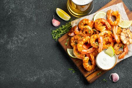 Grilled shrimps or prawns served with lime, garlic and white sauce on a dark concrete background. Seafood. Top view with copy space. Flat lay.の写真素材