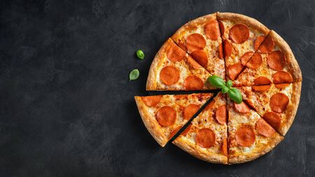 Tasty pepperoni pizza and cooking ingredients tomatoes basil on black concrete background. Top view of hot pepperoni pizza. With copy space for text. Flat lay. Banner.の写真素材