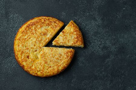 Spanish omelette with potatoes and onion, typical Spanish cuisine on a black concrete background. Tortilla espanola. Top view with copy space.の写真素材