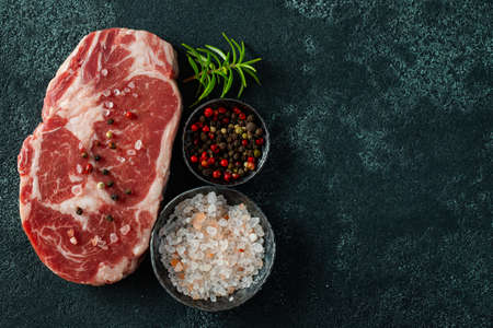 Raw fresh meat Ribeye Steak and seasoning on dark background. Top view with copy space. Flat layの写真素材
