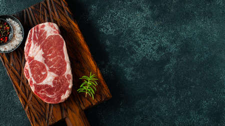 Raw fresh meat Ribeye Steak and seasoning on dark background. Top view with copy space. Flat lay.の写真素材