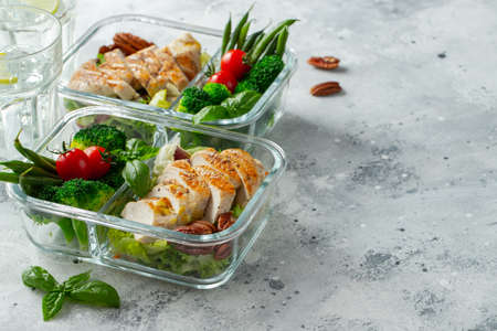 Healthy meal prep containers with green beans, chicken breast and broccoli. A set of food for keto diet in lunchbox on a light concrete background. Top view with copy spaceの写真素材