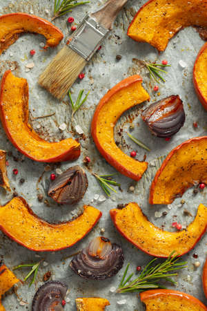 Closeup roasted pumpkin with addition aromatic herbs, red onion, sea salt and olive oil. Pumpkin autumn background. Top viewの写真素材