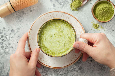 Cup of Matcha Green Tea in woman hands. Top view. flat lay