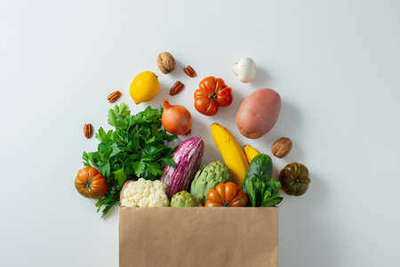 Healthy food background. Healthy vegan vegetarian food in paper bag vegetables and fruits on white,...