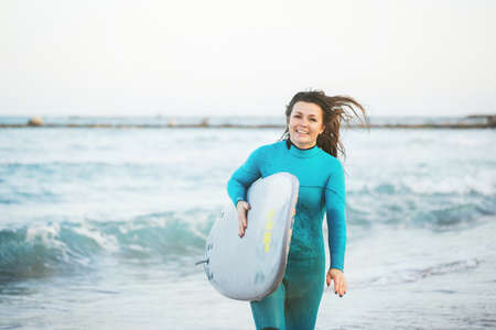 Surfer girl walking with board on the sandy beach. Surfer female.の写真素材
