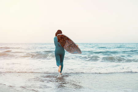 Surfer girl walking with board on the sandy beach. Surfer female.