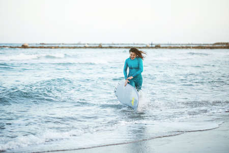 Surfer girl walking with board on the sandy beach. Surfer female.