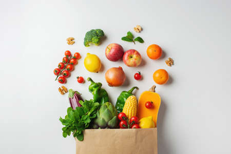 Delivery healthy food background. Healthy vegan vegetarian food in paper bag vegetables and fruits on white. Shopping food supermarket and clean vegan eating concept.の写真素材