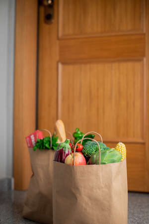 Food shopping bags stand at the door of the house or apartment. Vegetables and fruits delivery...