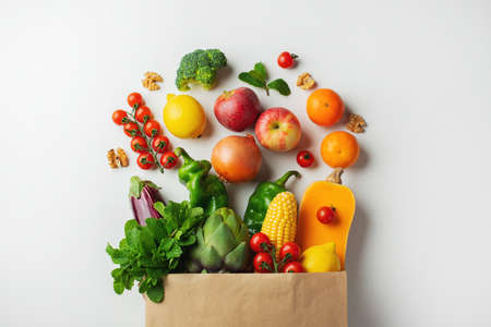 Delivery healthy food background. Healthy vegan vegetarian food in paper bag vegetables and fruits on white, copy space, banner. Shopping food supermarket and clean vegan eating conceptの写真素材