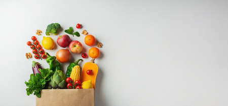 Delivery healthy food background. Healthy vegan vegetarian food in paper bag vegetables and fruits on white, copy space, banner. Shopping food supermarket and clean vegan eating concept.の写真素材