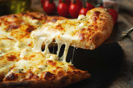 A slice of hot Italian pizza with stretching cheese. Pizza four cheeses with basil.の写真素材