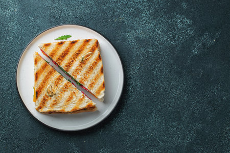 Two homemade sandwiches with sausage, cheese and arugula on a dark concrete background. The concept of a quick meal or snack at work or school. top view with copy spaceの写真素材