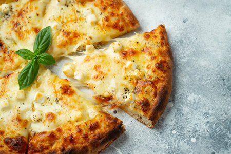 Italian pizza four cheeses with stretching cheese and basil on a light concrete background.の写真素材