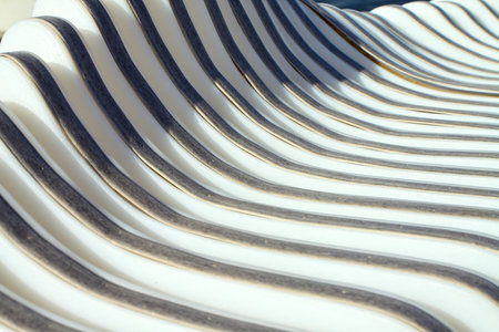 A close-up of an abstract texture with repeating curved lines and deep shadows. Creates the effect of waves or a textured surfaceの写真素材