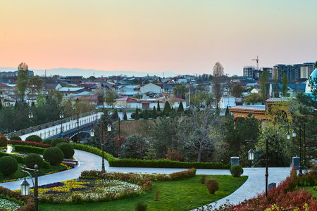 Well-groomed paths, ornamental shrubs and a panorama of the city against the backdrop of the dawn sky create an atmosphere of comfort and tranquilityの写真素材