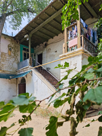 Vertical shot of the facade of an old residential building with peeling walls, an exterior staircase leading to a wooden veranda, and laundry hangingの写真素材