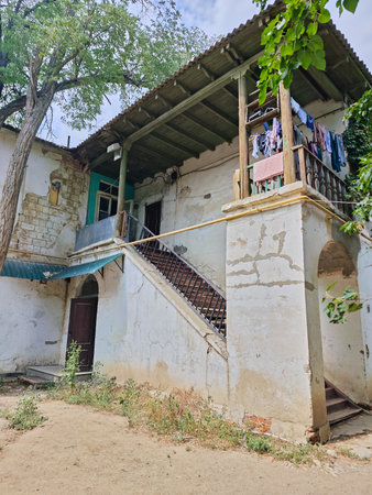 Vertical shot of the facade of an old residential building with peeling walls, an exterior staircase leading to a wooden veranda, and laundry hanging.の写真素材