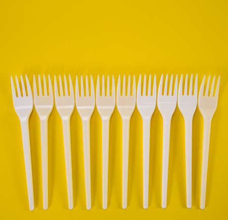 Plastic forks in one row on a yellow backgroundの写真素材