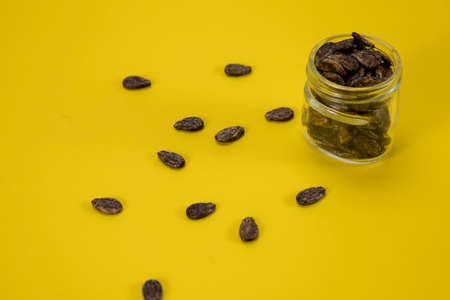 A jar of watermelon seeds is raced around on a yellow backgroundの写真素材