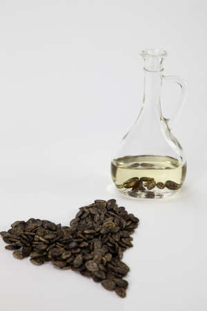 Heart of watermelon seeds on a white background and a bottle of oil from watermelon seeds, on a white backgroundの写真素材
